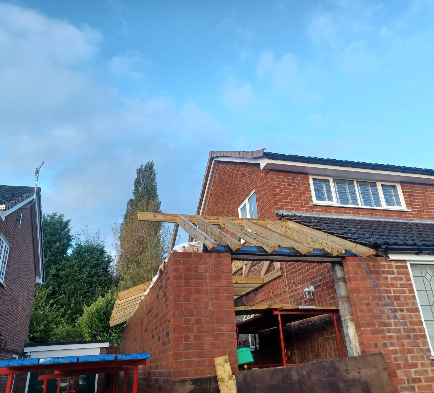 Roof trusses going up on a brick extension