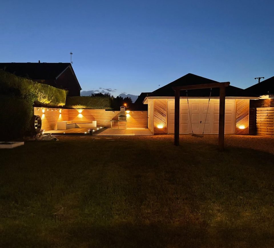 A completed Gilbert O'Neill garden and outbuilding project lit at dusk